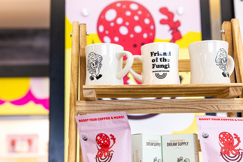 Display shelf at the Wunderground kiosk showing mushroom‑themed mugs and packaged products.