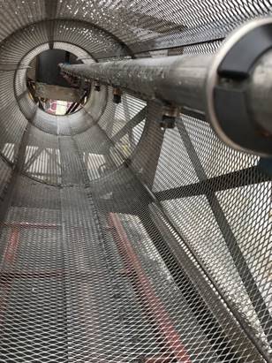 A view from inside a cylindrical metal drum with mesh walls and a central rotating pipe, part of the Port’s media washing machine used to clean oyster shells and other coarse media.