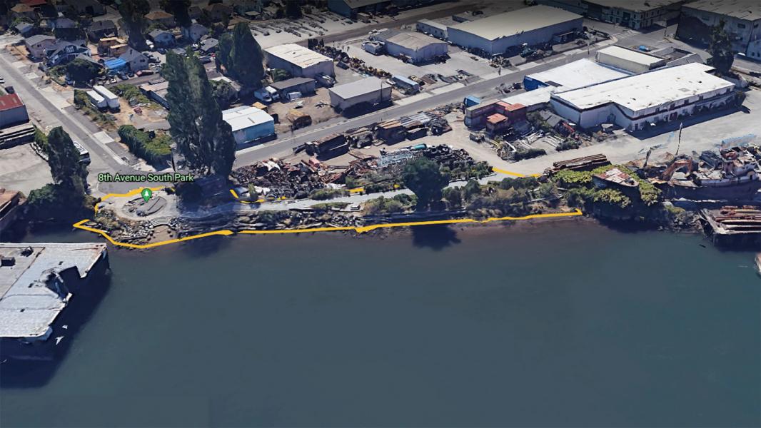 Aerial view of a waterfront path marked in yellow along an industrial shoreline.