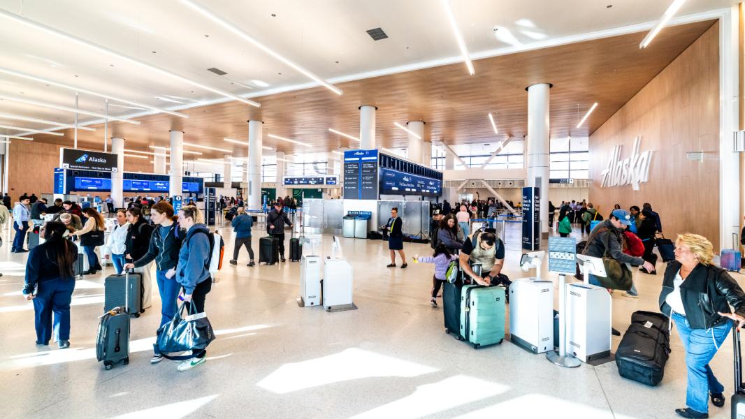 Passengers move about the new Alaska Ticketing Lobby, using the new check-in kiosk technology. The renovated lobby is lighter, brighter, and more modern, with higher ceilings, upgraded digital signage, and more convenient features to make the journey easier