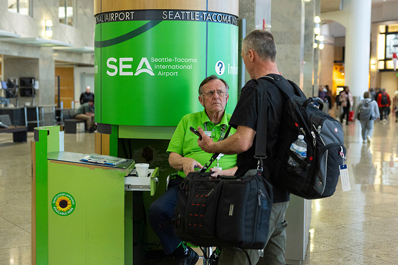 Traveler speaking with an information desk worker at Seattle‑Tacoma International Airport.
