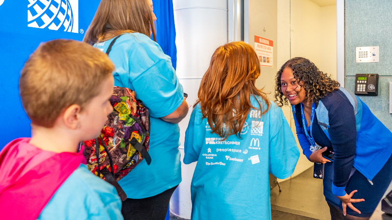 A United Airlines representative welcomes Wings for All participants aboard a commercial aircraft