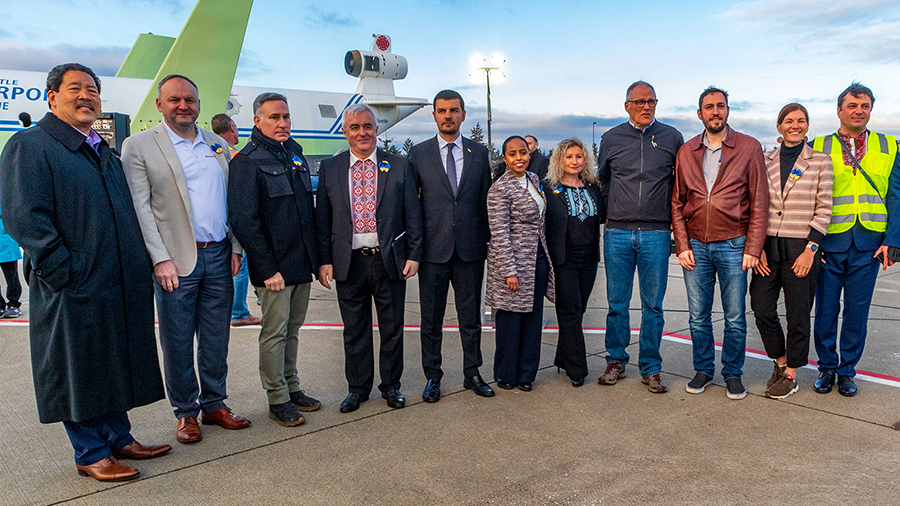 Governor Inslee with other leaders from the county, city and local municipalities pose on the airfiels at SEA with cargo planes behind filled with humanitarian supplies for Ukraine.