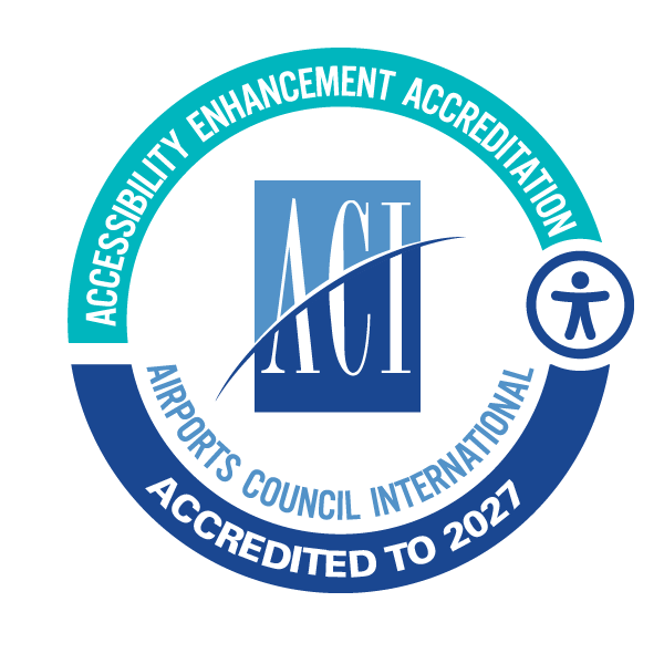 Badge with the ACI logo in the center, surrounded by a circular ring of text that reads ‘Accessibility Enhancement Accreditation,’ ‘Airports Council International,’ and ‘Accredited to 2027.’ A universal accessibility symbol appears on the right side of the ring.