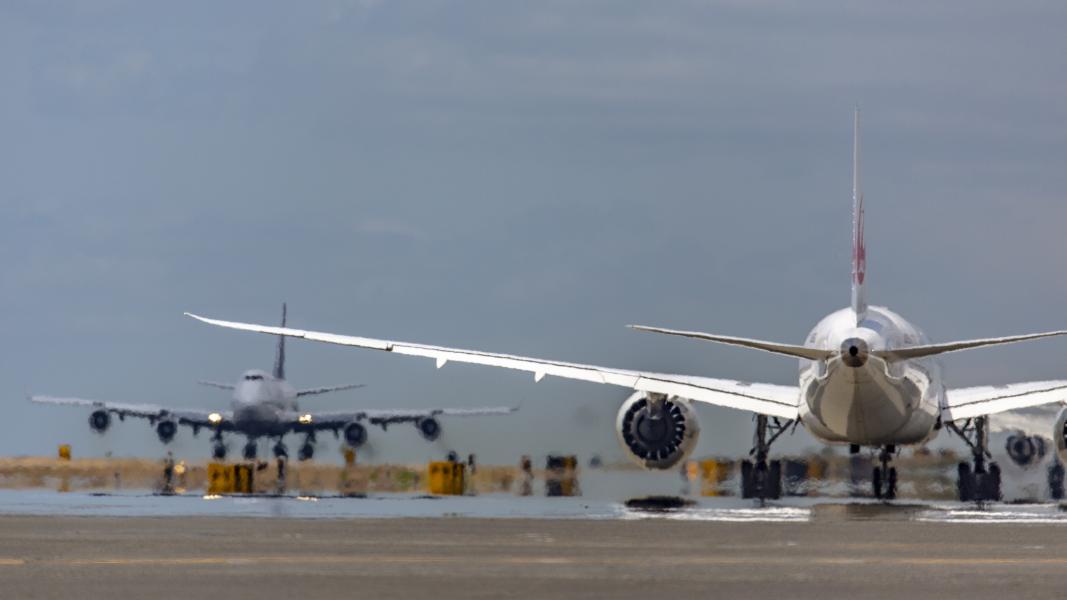 A close-up view of two commercial airplanes on an active runway at Sea Airport, with one aircraft in the foreground and another lined up behind it, both positioned for taxi or takeoff.