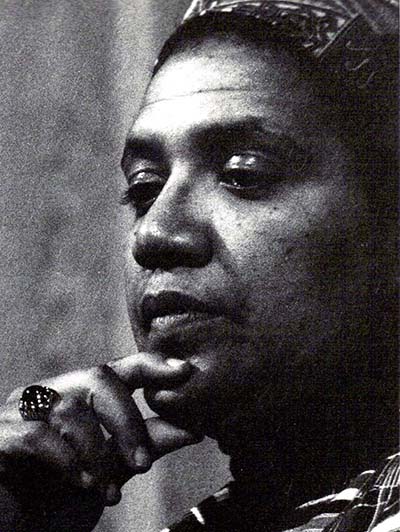 Black‑and‑white close‑up portrait of a Audre Lorde with a thoughtful pose, resting a hand near the chin. 