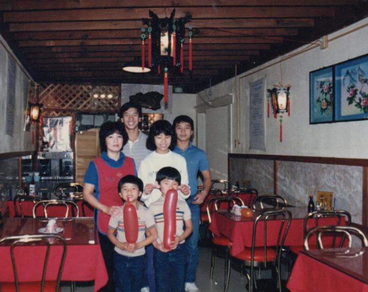 A dated photograph of Daniel Nguyen and his family standing in a small restaurant together.