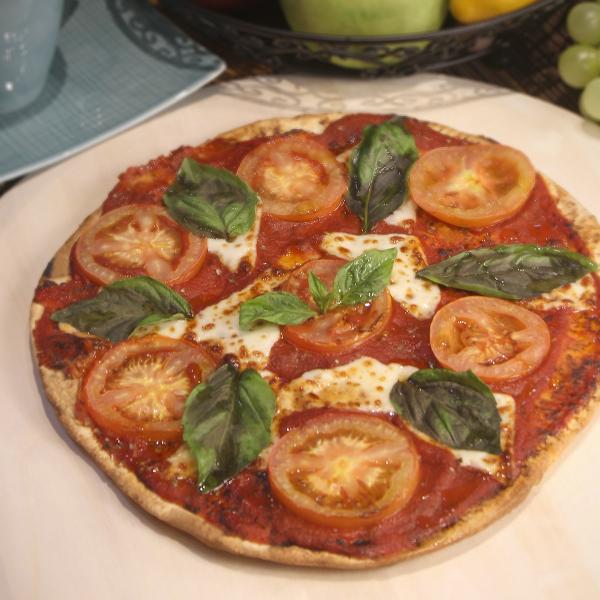 A pizza with tomatoes, basil, and cheese.. 