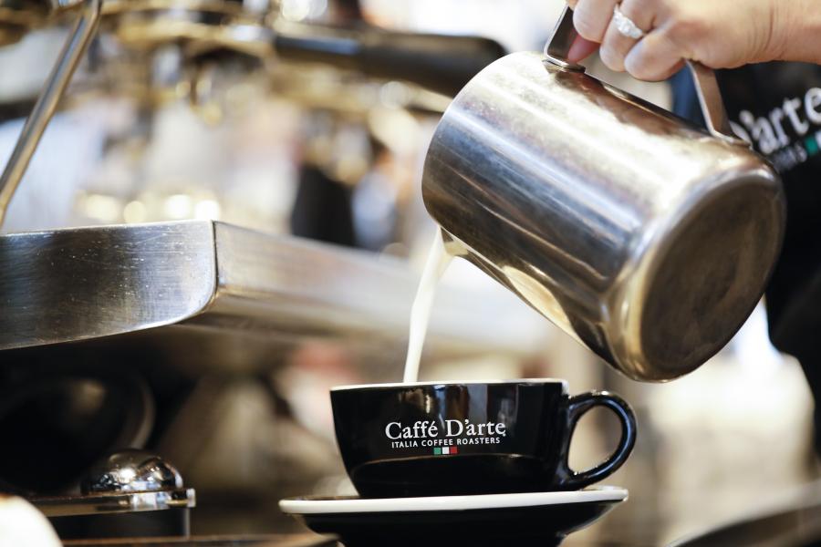 Up close shot of barista pouring milk into a latte at Caffe D'arte.