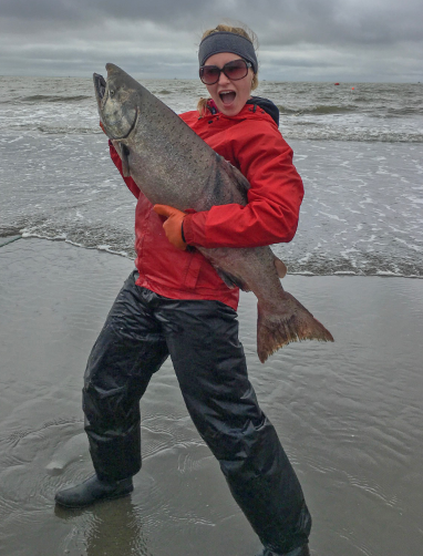 Evelyn Clark on the beach holding a salmon.