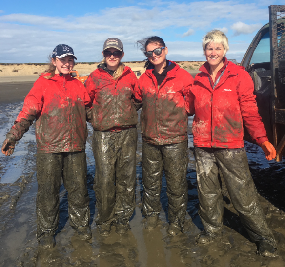 Evelyn Clark covered in mud standing next to three other women wearing fishing gear.