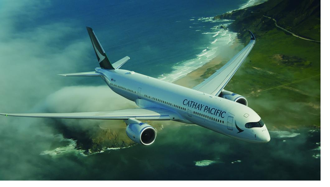 "Cathay Pacific aircraft flying over a coastline with clouds, ocean waters, and green cliffs below.