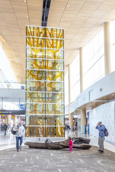 Tall glass sculpture with brass log in front.