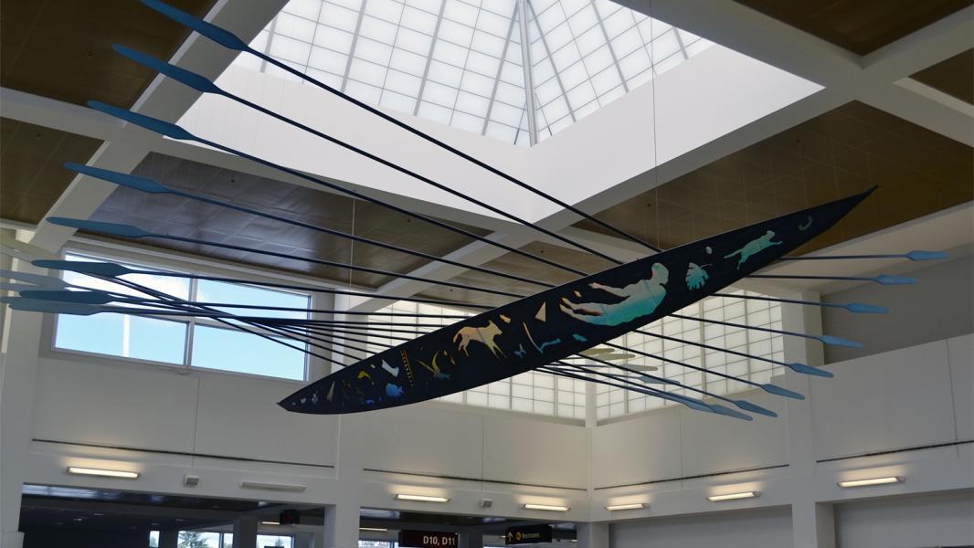 Painted canoe art installation hanging in the D Concourse of SEA Airport