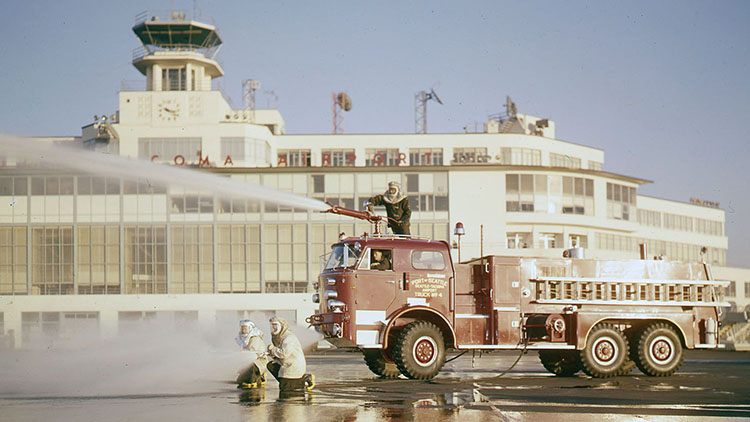 1960s Pumper firefighters using large hoses on the airfield.
