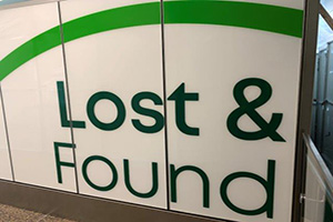 Large wall sign reading Lost and Found in bold green letters in an airport hallway.
