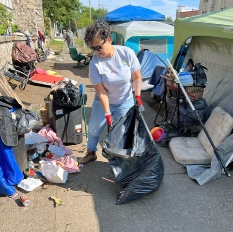 Nicole picking up trash and debris around an encampment