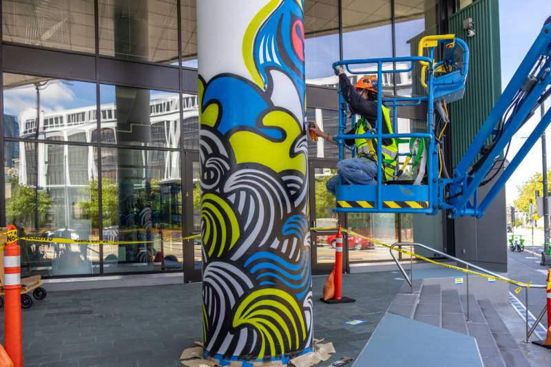 Photo of colorful artwork being painted on one column outside the Port’s headquarters