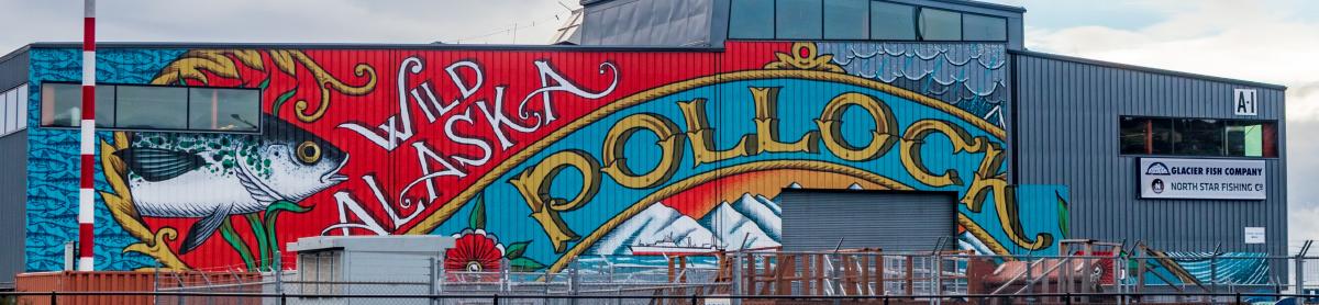 A colorful mural on a building features a large fish and the words “Wild Alaska Pollock.”
