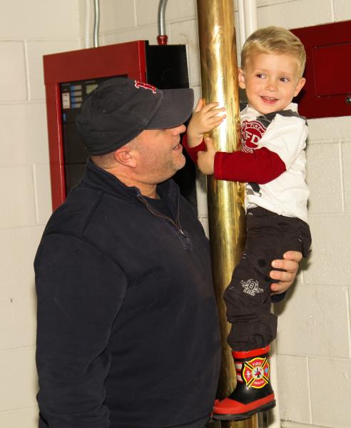 Todd Starkey with a child on a fireman pole.