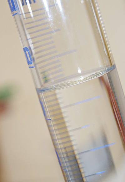 Close-up of a clear test tube partially filled with liquid, showing blue measurement markings.
