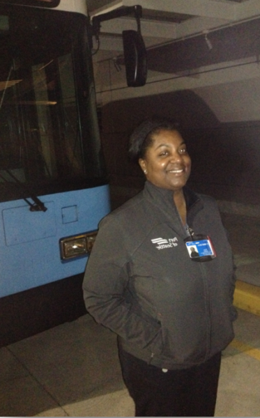 Monica Petty standing beside a bus inside a transit facility.