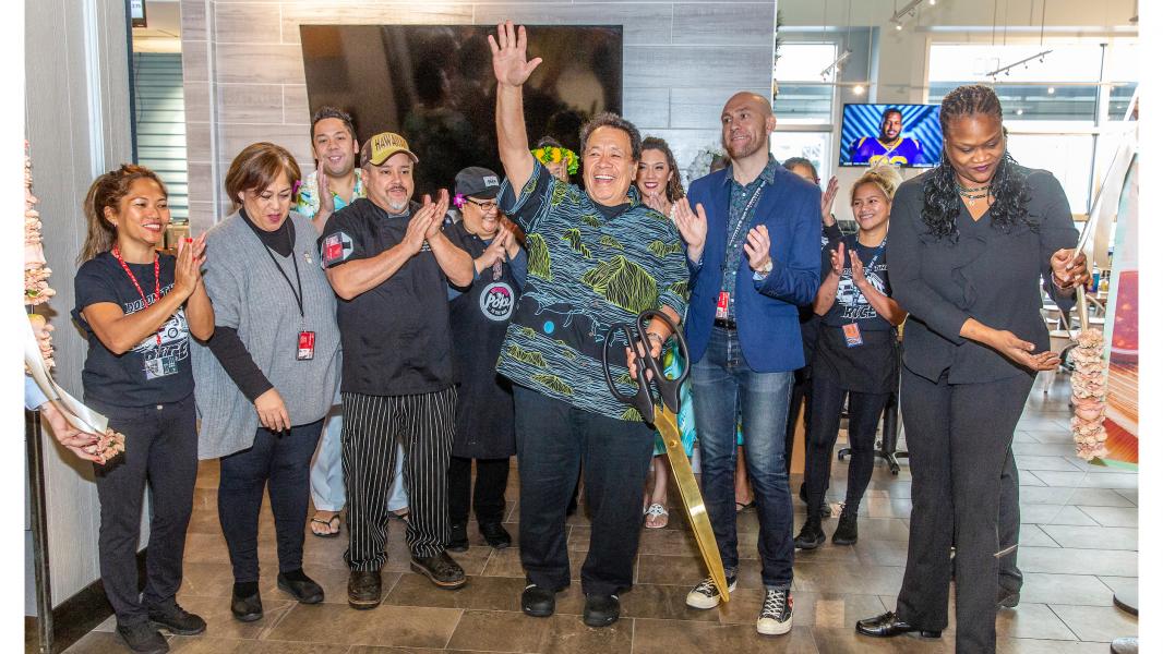 A group gathers inside the new Poke to the Max location at SEA Airport for a ribbon‑cutting celebration marking the restaurant’s opening, led by Sam Choy.