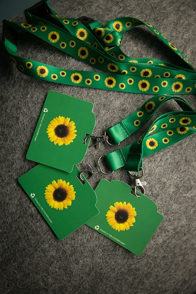 Green sunflower lanyards and matching cards with sunflower symbols arranged on a gray surface.