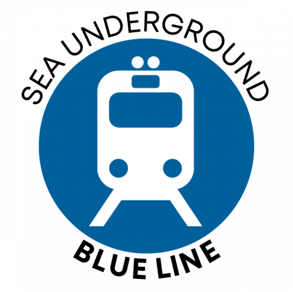 Circular blue icon featuring a simplified white front‑view train symbol. The words ‘SEA UNDERGROUND’ curve above the circle and ‘BLUE LINE’ curve below.