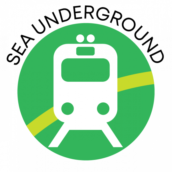 Circular green icon with a simple white front view of a train on tracks, a yellow curved line behind it, and the words ‘SEA UNDERGROUND’ arched above the circle.