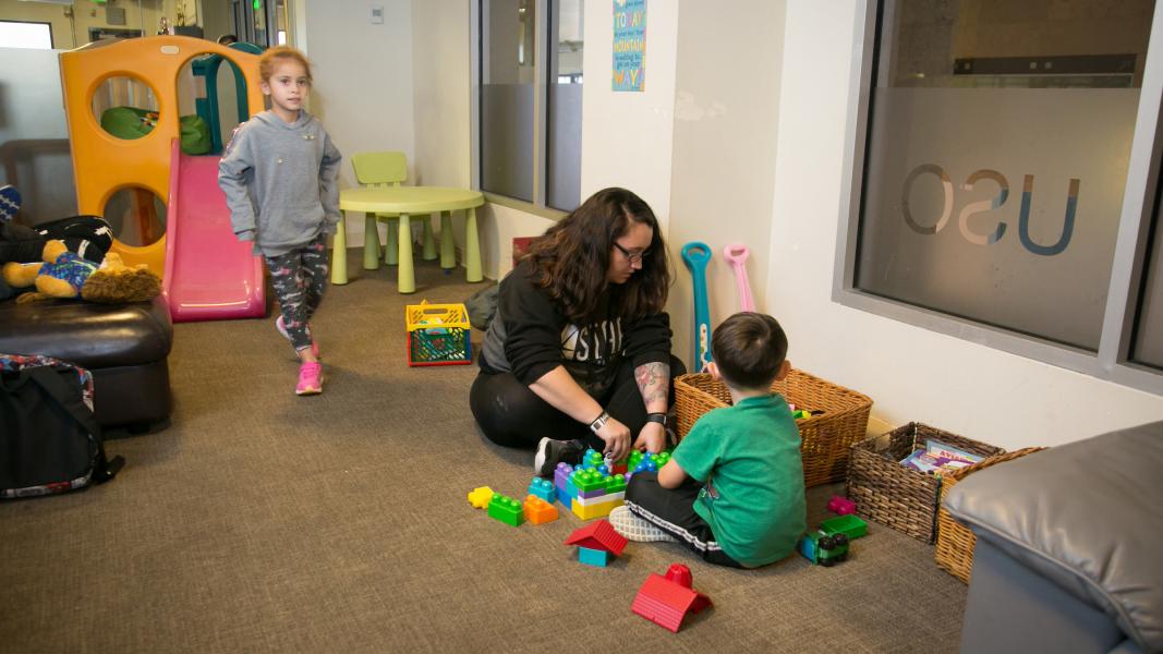 Two children and a caretaker play in the USO daycare.