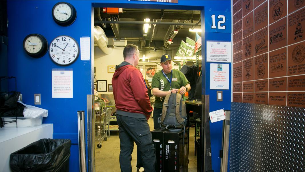 A volunteer helping a veteran with his backpack.