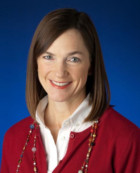 Corporate headshot of Linda Styrk smiling against a blue background.