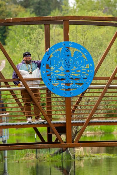 Ty Juvinel taking a photo next to his art at ƛ̕ax̌ʷadis (TI' awh-ah-dees) Park in Kenmore