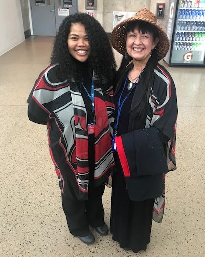 Two women dressed in Native outfits at SEA Airport.
