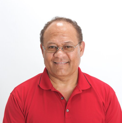 Tony Puloka wearing glasses and a red collared shirt looks toward the camera against a plain white background.
