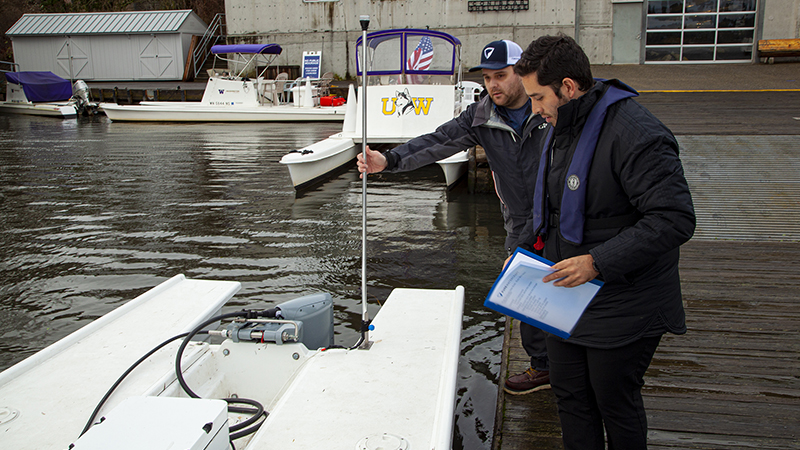 Two men inspecting a small boat motor.