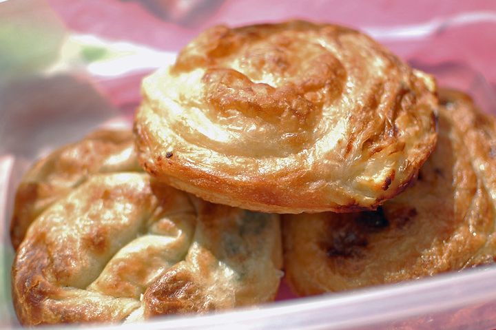 Three pieces of golden-brown burek with flaky, layered pastry stacked together on a plate.