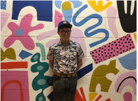 Adrian Down in front of a colorful wall mural.