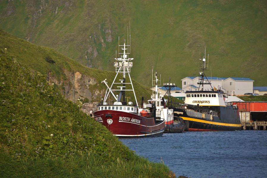 Fishing boats docked beside green hills in Dutch Harbor, Alaska.
