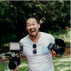 Derek Edamura holds camera equipment.