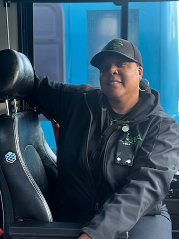  Katrina Taplin wearing SEA-branded clothing seated inside a vehicle, holding onto the seat.