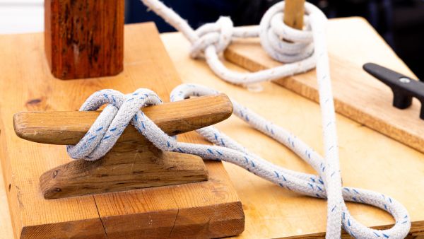 Close-up of ropes tied in demonstration knots on wooden posts and cleats.