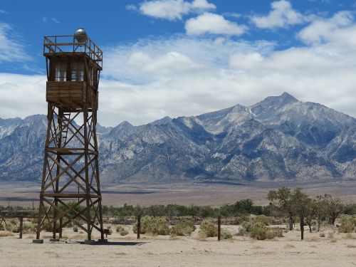 Manzanar guard tower with barbed wire and mountains.