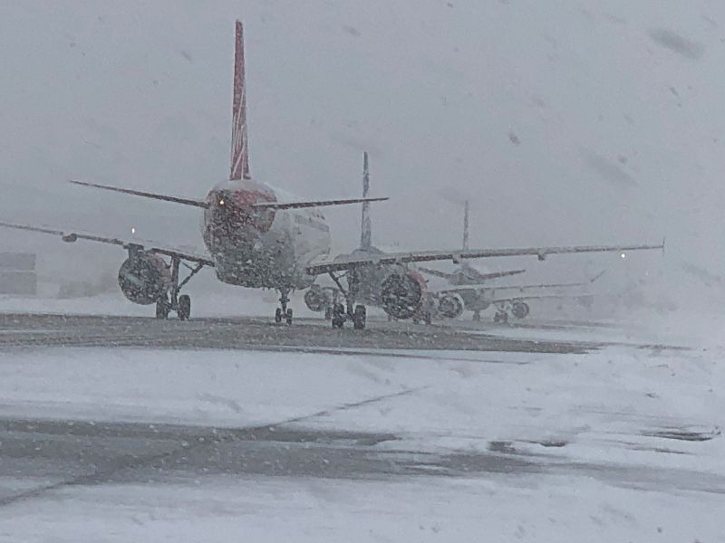 Planes on the runway during a snow storm.