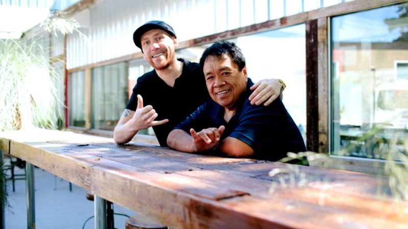 The story’s subjects, Sam Choy and business partner Max Heigh, are shown in an outdoor seating area at their newly opened Poke to the Max location at SEA.