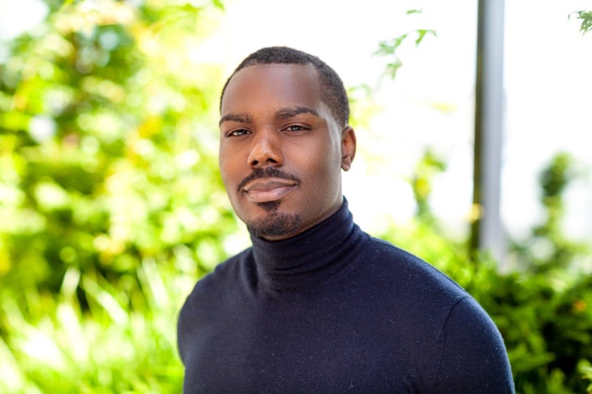 Headshot of Sean McDonald, shown outdoors with greenery in the background.