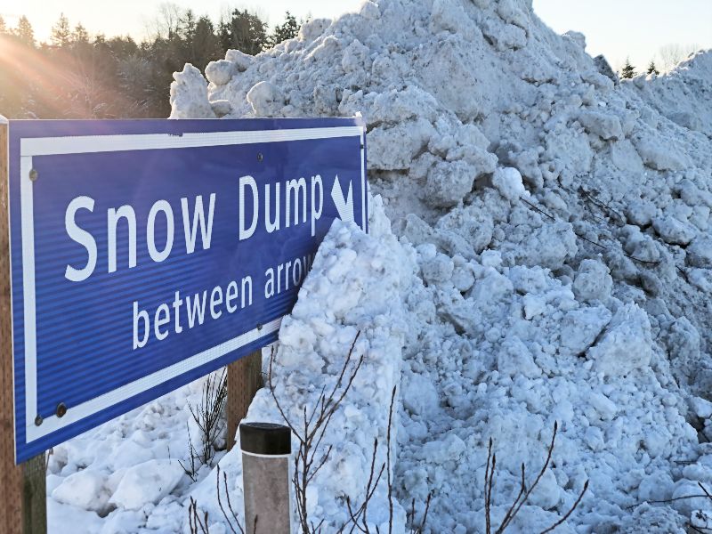 Snow dump sign with a large pile of snow beside it.