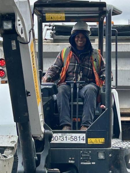 Tiffany English sitting in a construction vehicle wearing a hard hat and safety vest.