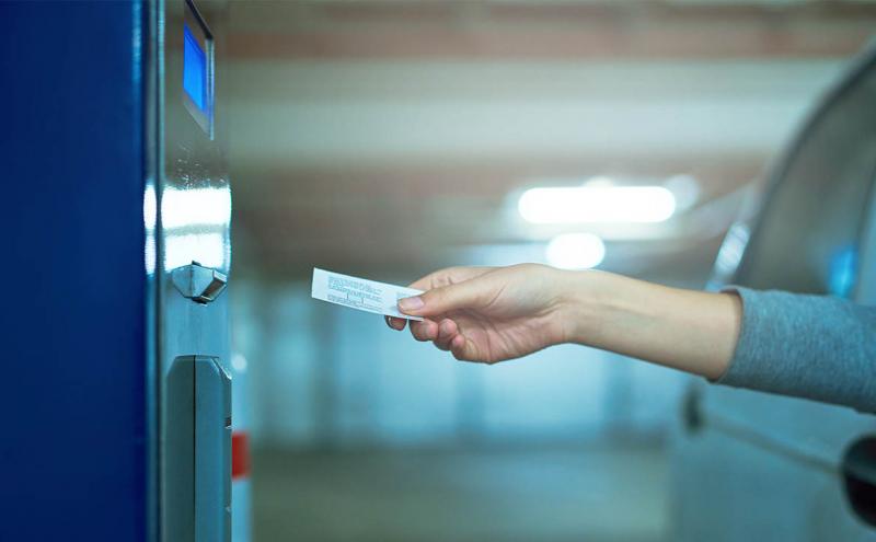 A person inserting a ticket into a payment machine.